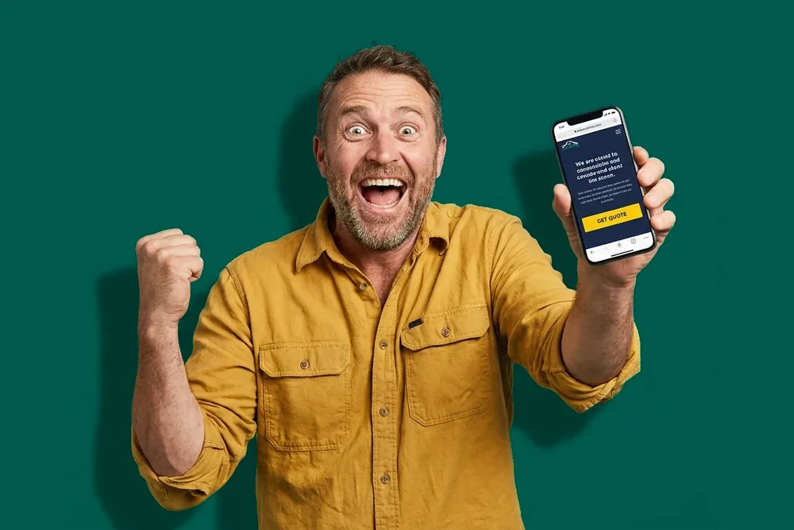 A delighted small business owner holding a phone showing their brand-new website